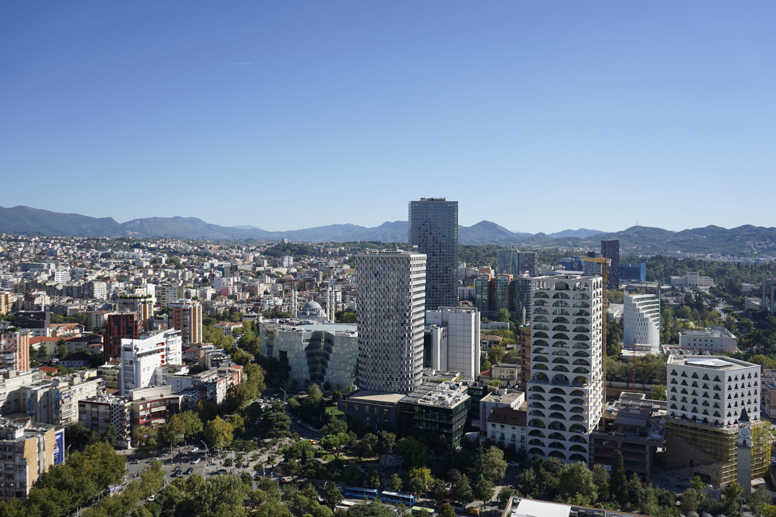 Wide Tirana skyline with dense city buildings and mountains beyond the capital.