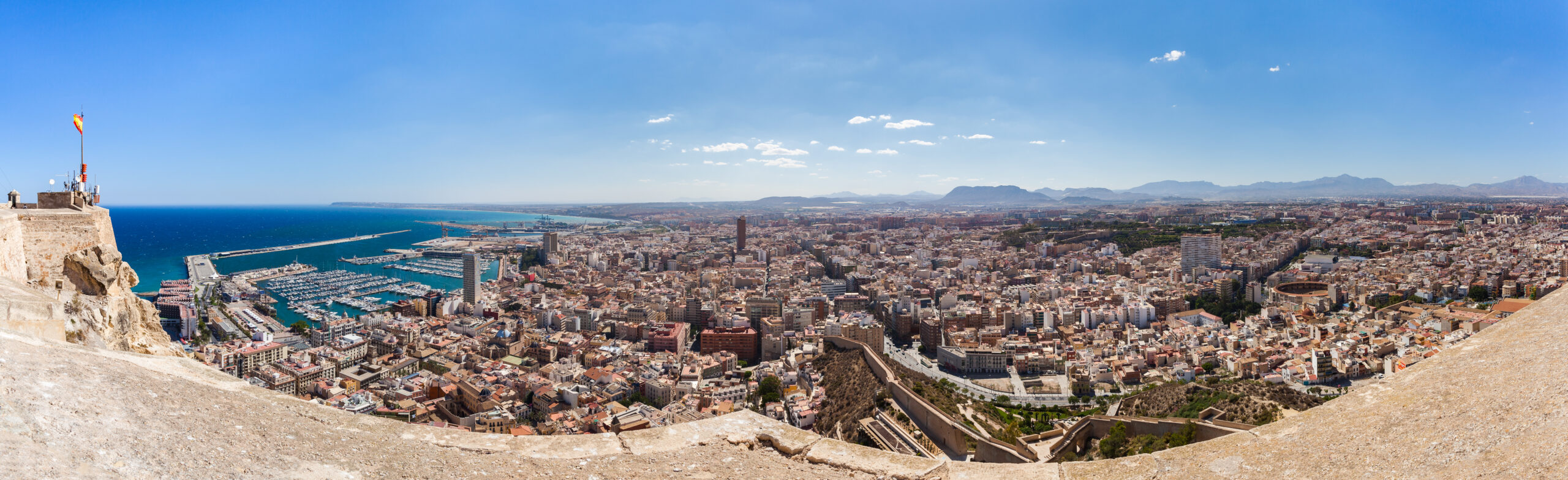 Alicante city and marina view showing the waterfront, boats, and surrounding urban area.