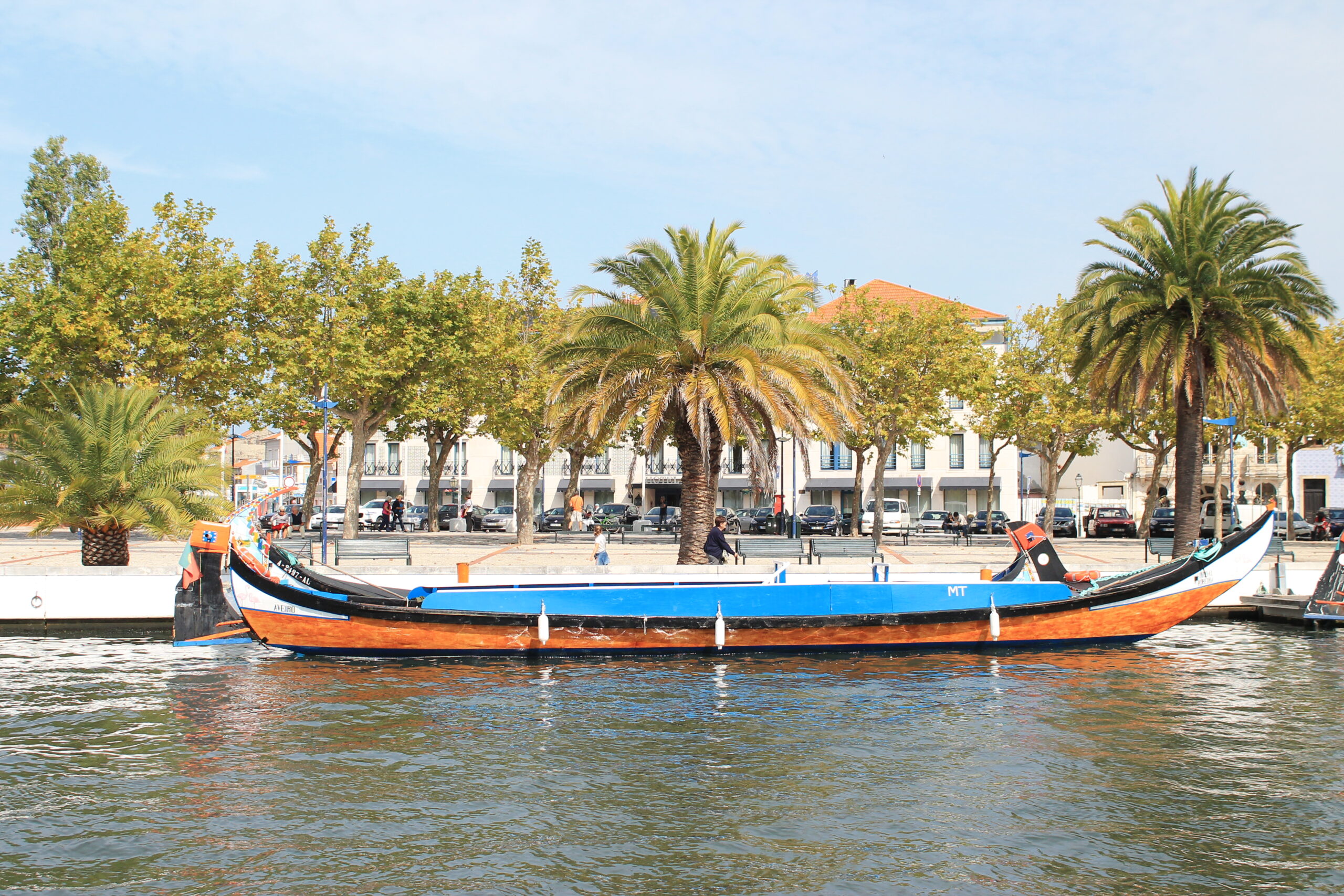 Colorful moliceiro boat moving through a sunny canal in Aveiro.