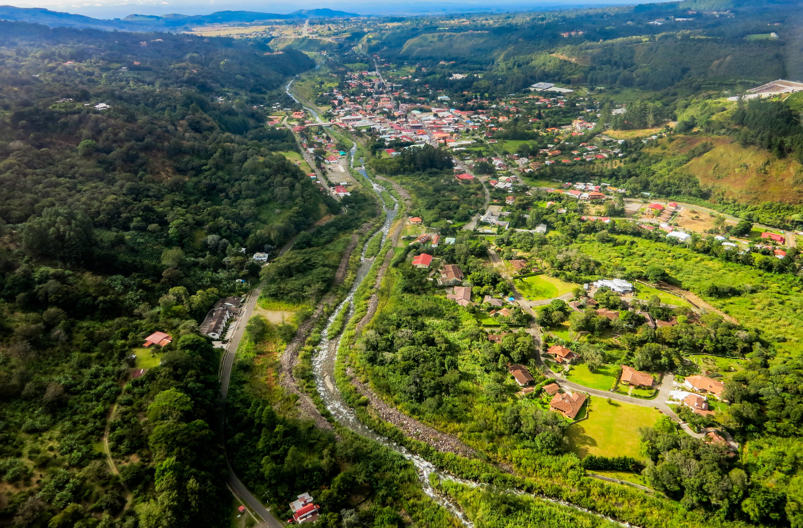 Aerial view over Boquete with green hills, scattered buildings, and a calmer inland mountain setting.