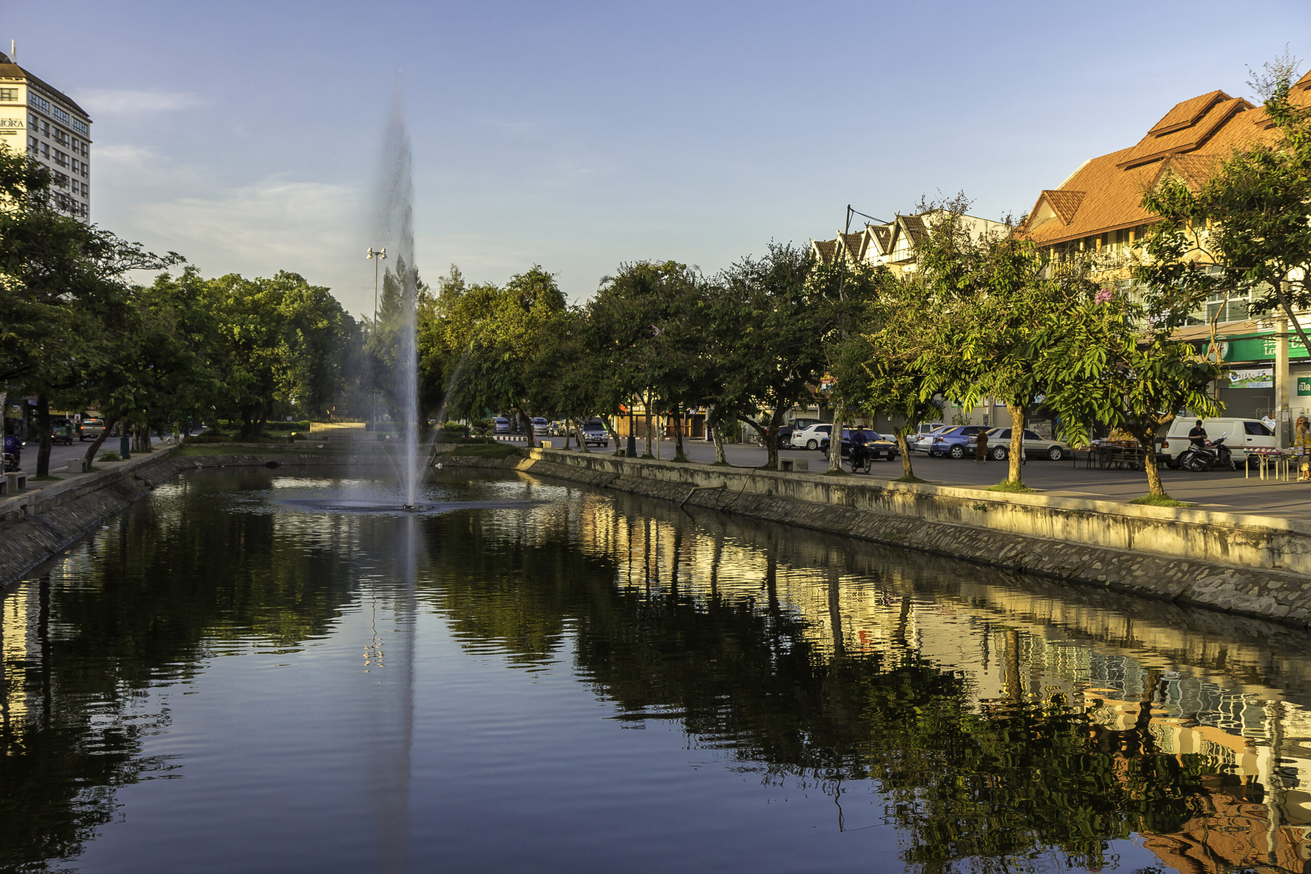 Tree-lined stretch of Chiang Mai moat with water, greenery, and a calm urban setting.