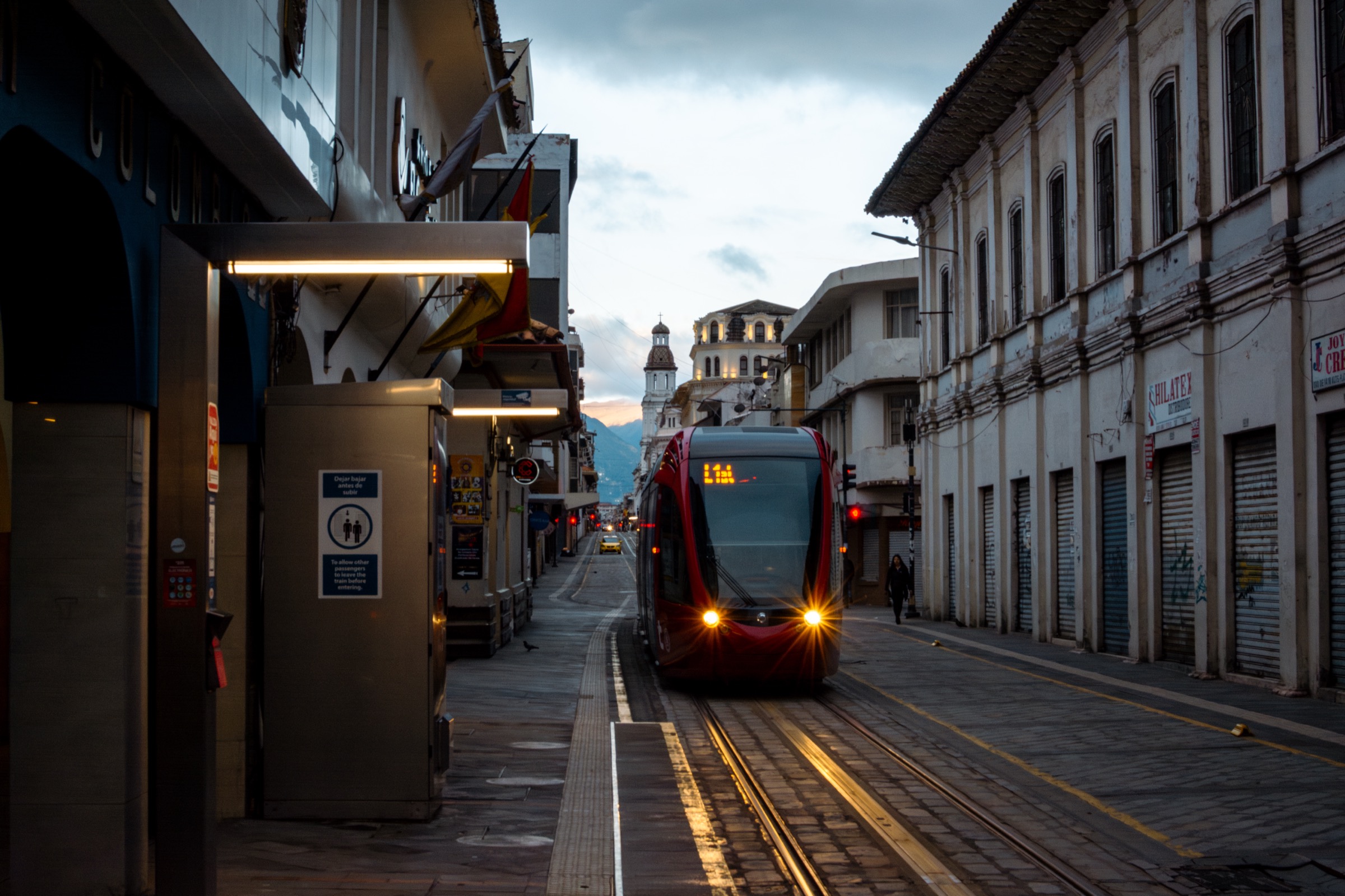 Red Cuenca tram moving through the historic center in early daylight.