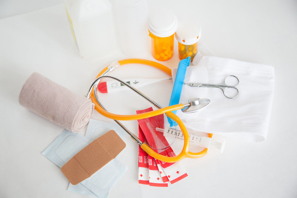 Medication bottles, basic medical supplies, and a stethoscope arranged on a bright table.