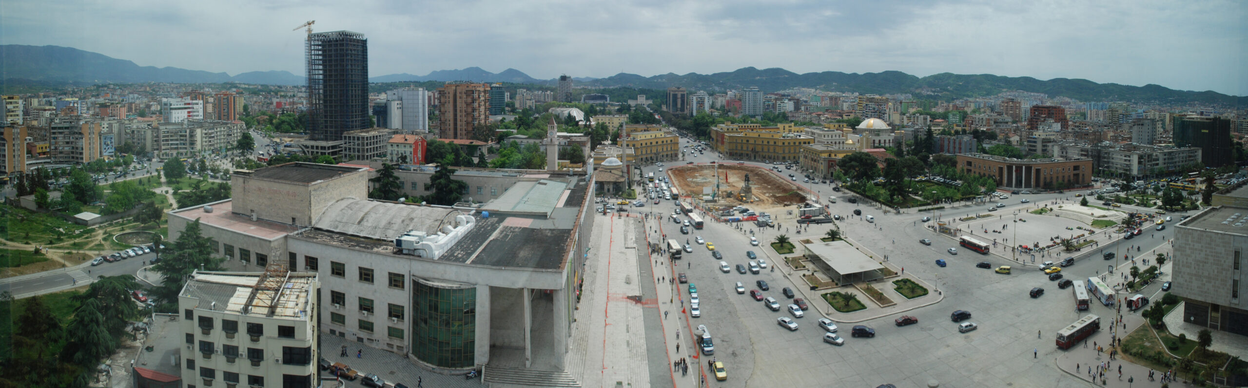Wide panorama across Tirana with mountains in the background and the city spread below.