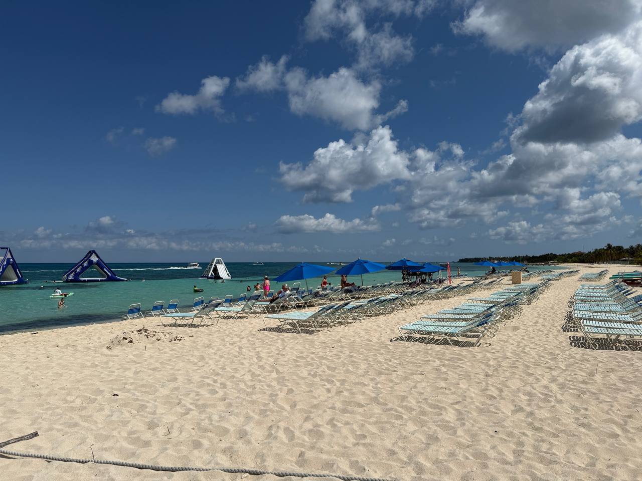 Private beach setup in Cozumel with loungers, umbrellas, and bright blue water during a catamaran stop.