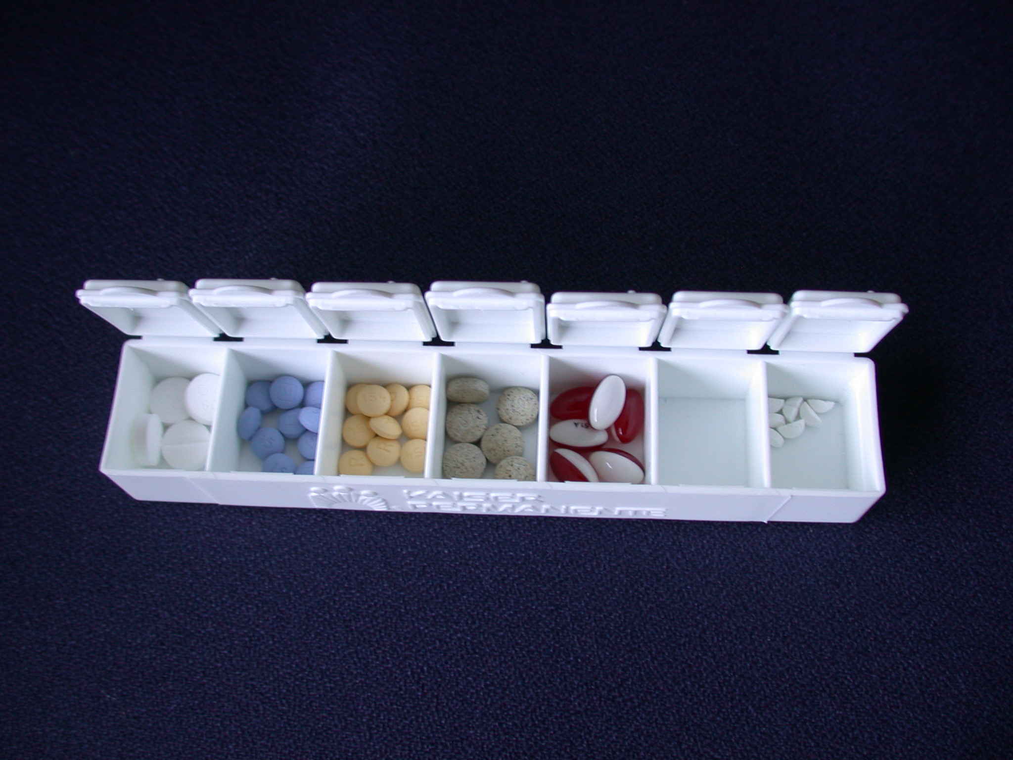 Open pill box with sorted medication compartments.