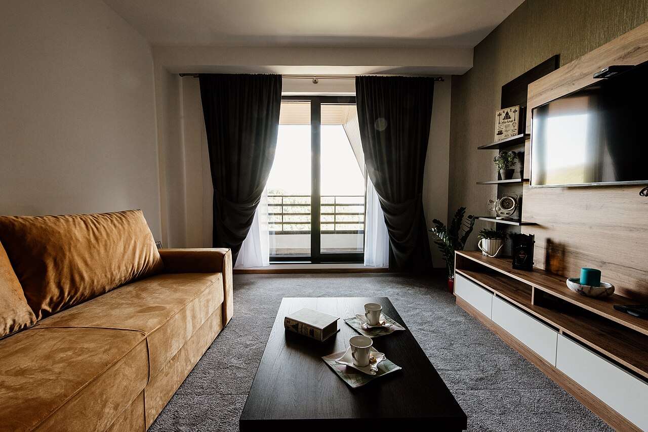 Bright apartment living room with sofa, coffee table, and large windows.