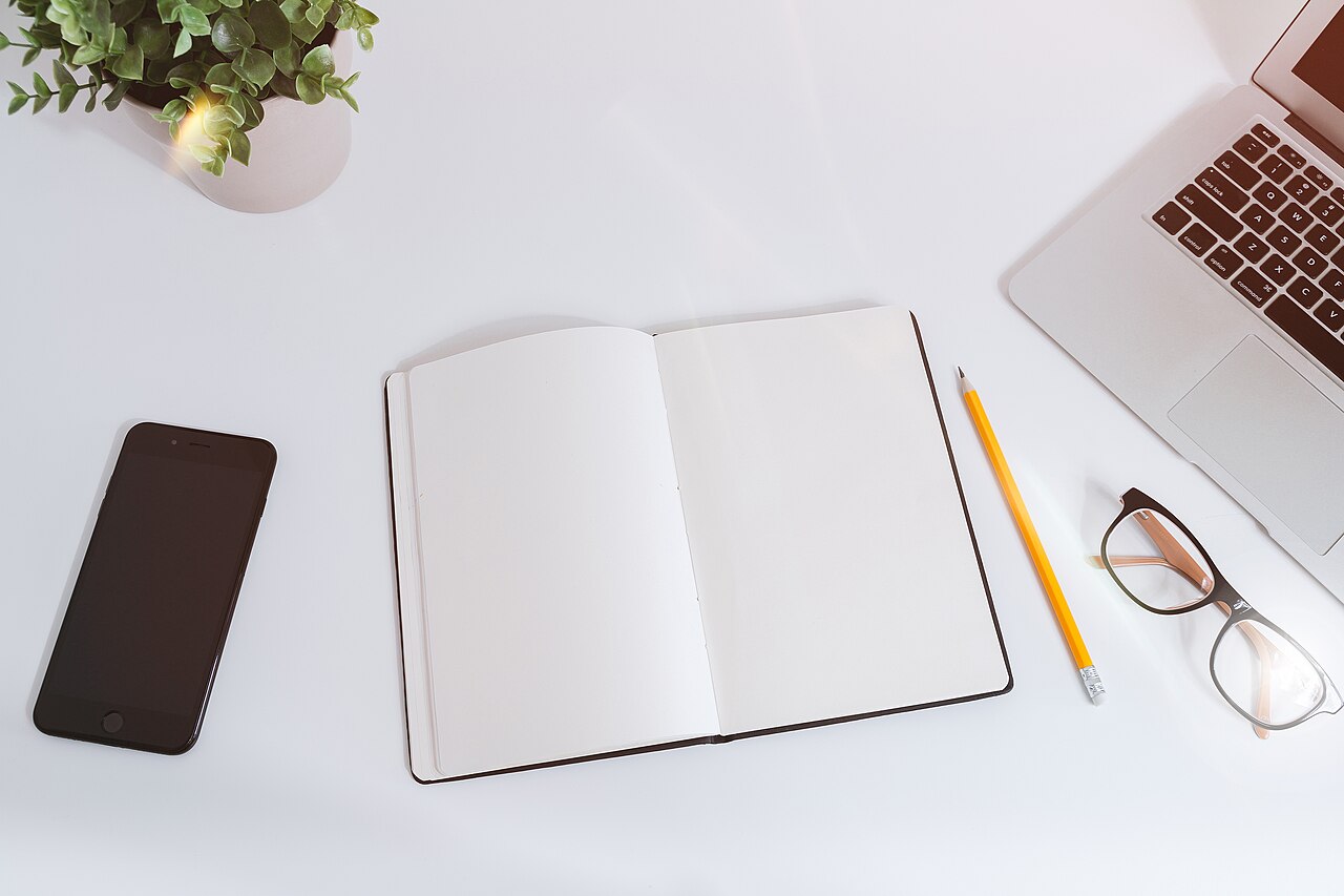 Laptop, phone, and notes arranged on a white work table.