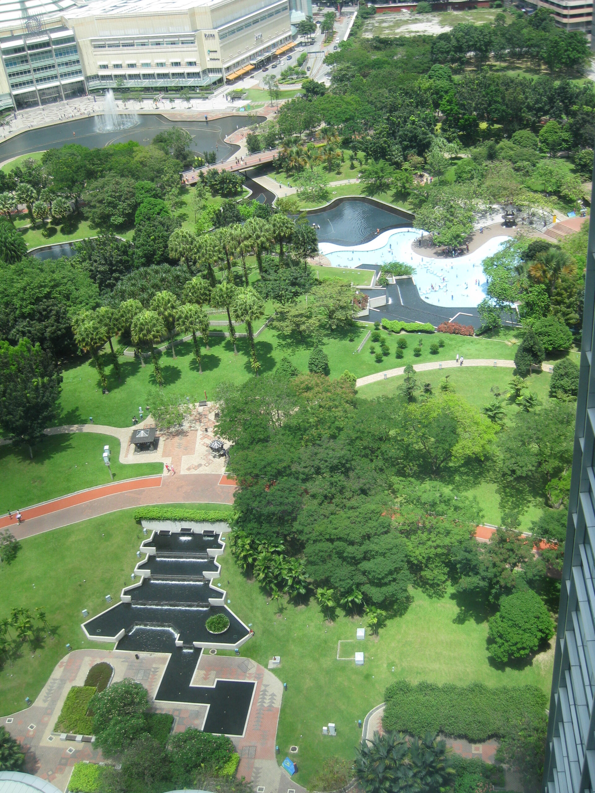 Green open area at KLCC Park with modern Kuala Lumpur towers rising behind the trees.