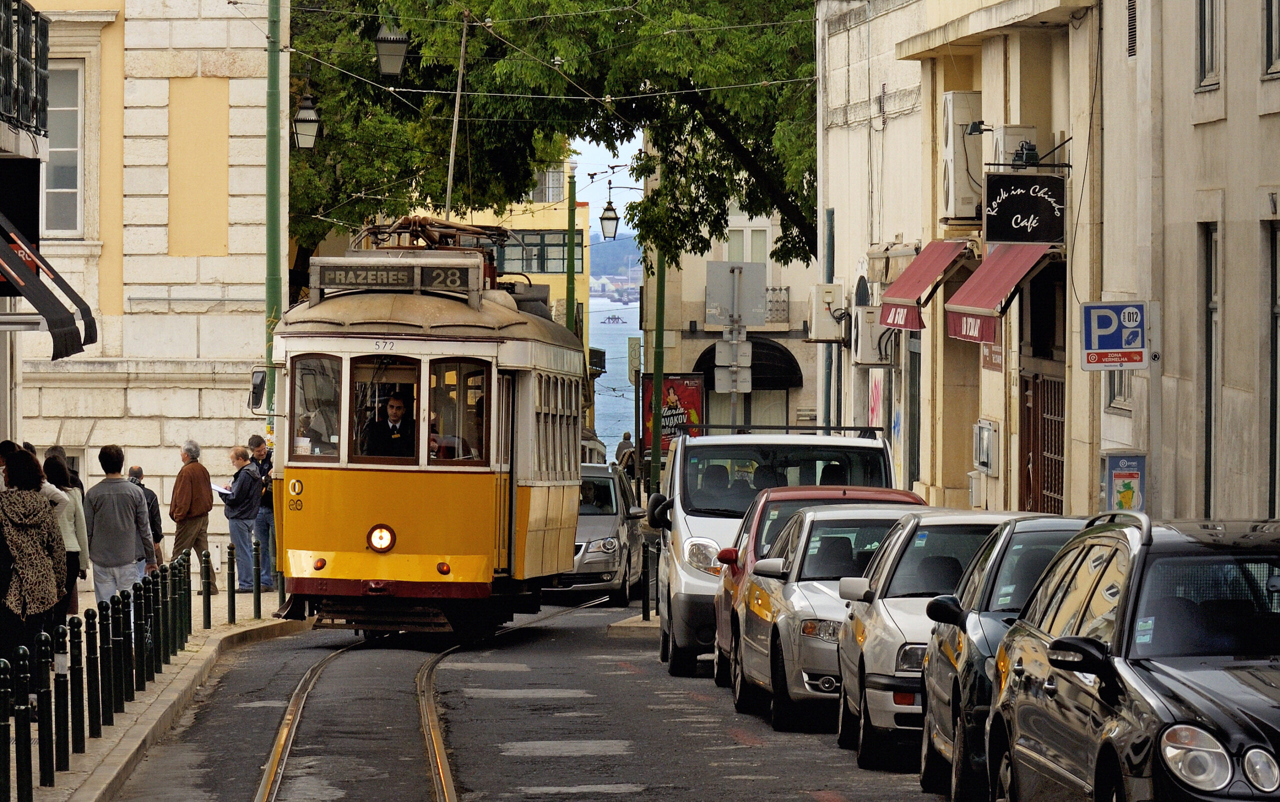 Classic yellow Lisbon tram moving through a narrow city street.
