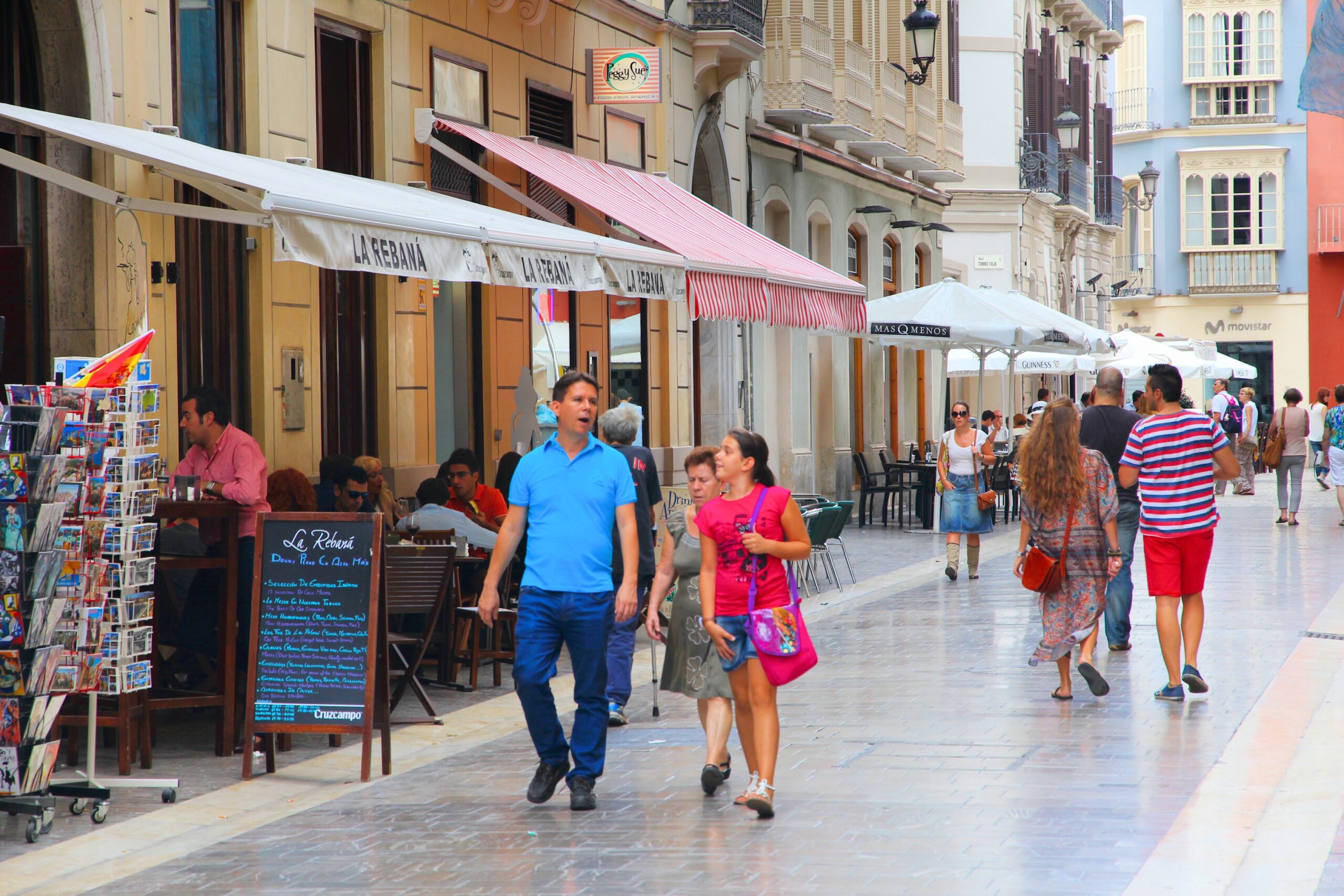 Pedestrian street in central Malaga with shops, awnings, and people walking through the old center.
