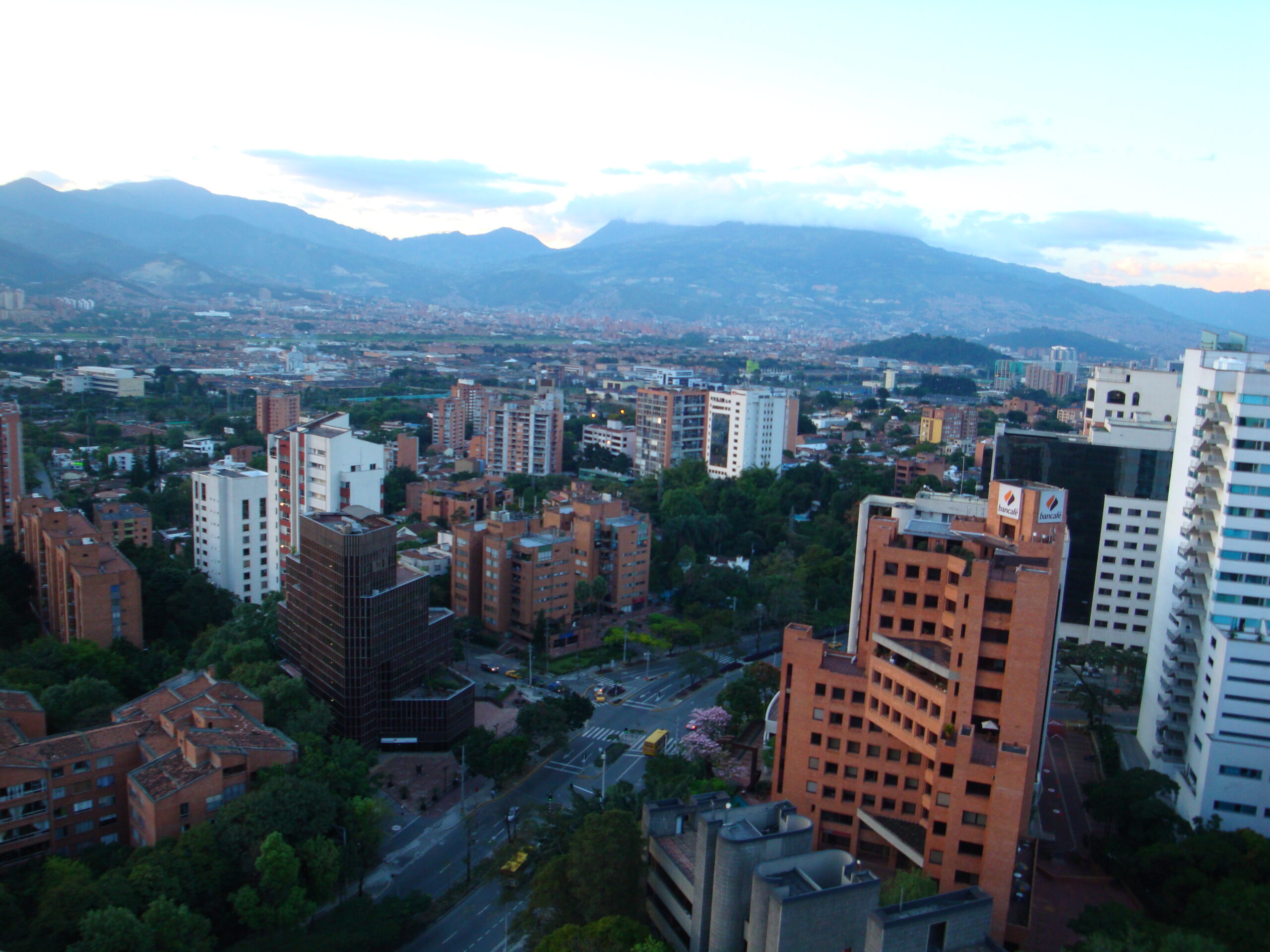Wide Medellín valley skyline under bright daylight with mountains rising behind the city.