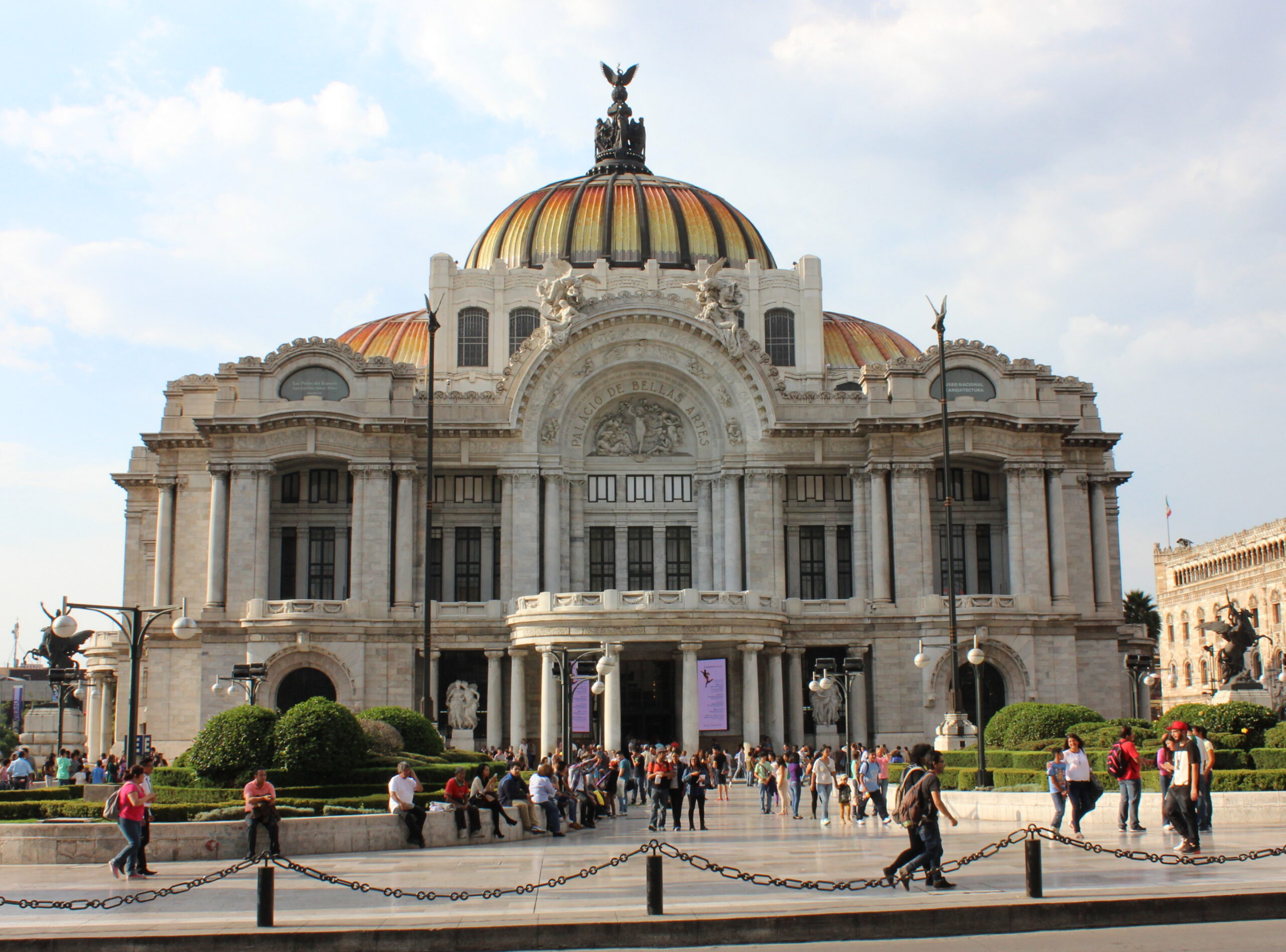 Front view of Palacio de Bellas Artes in Mexico City with pedestrians crossing the plaza.