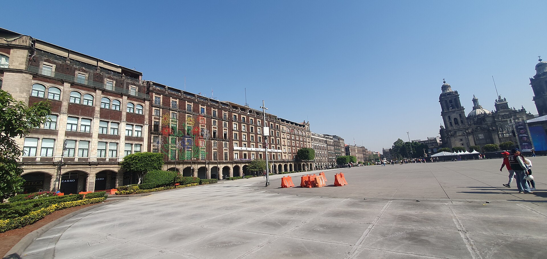 Wide Mexico City Zocalo scene with historic buildings and everyday urban activity.