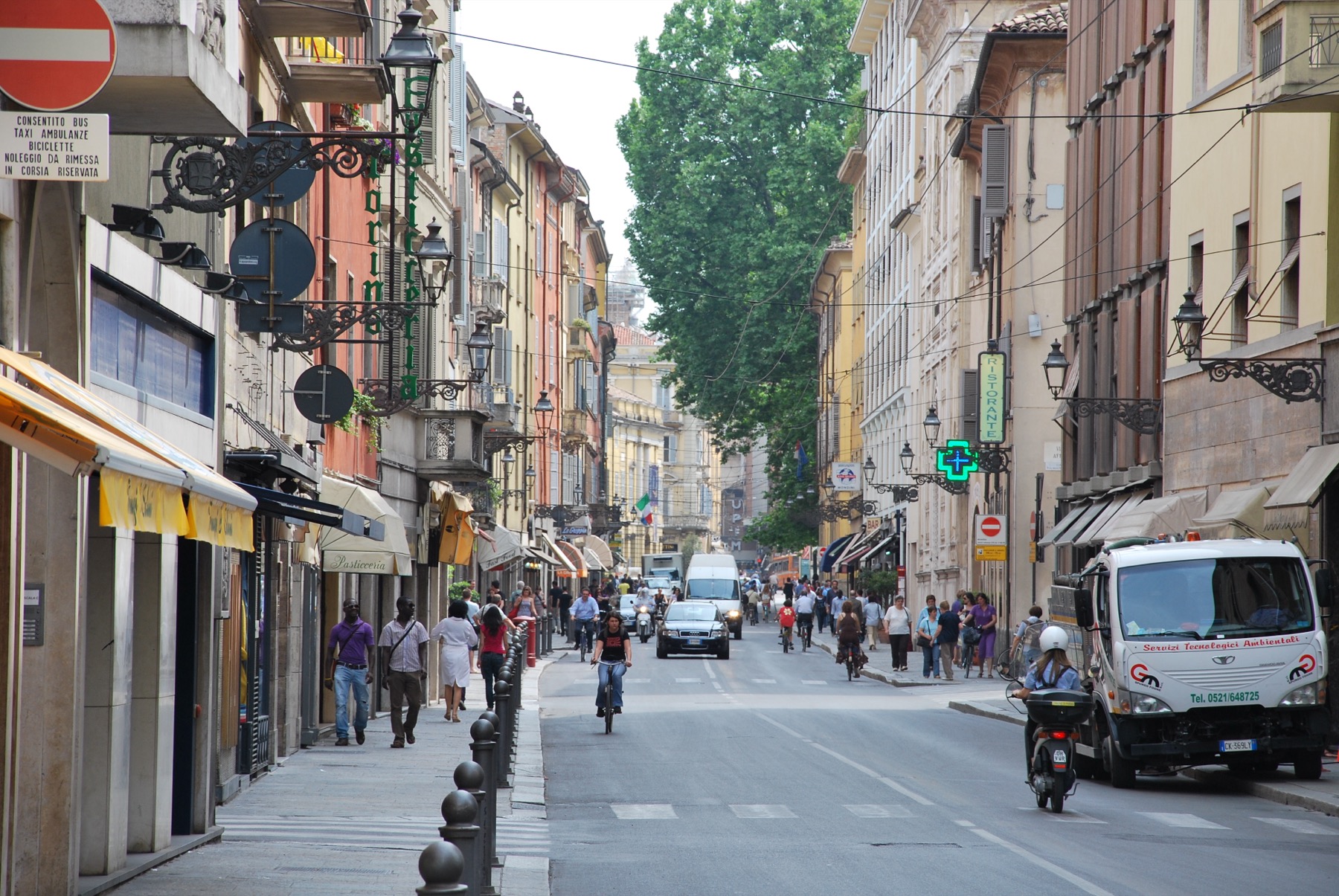 Street scene in Parma with shops, pedestrians, and everyday city activity.
