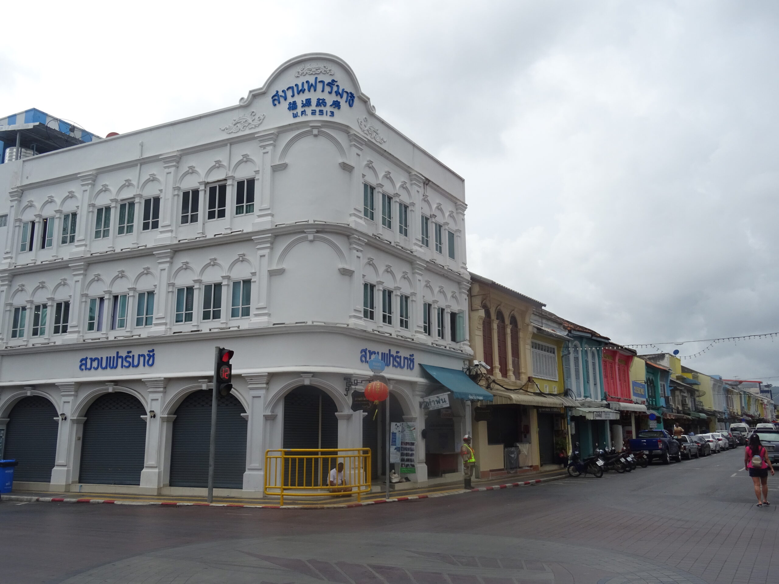 Colorful old-town block on Thalang Road in Phuket with shopfronts, pedestrians, and street activity.
