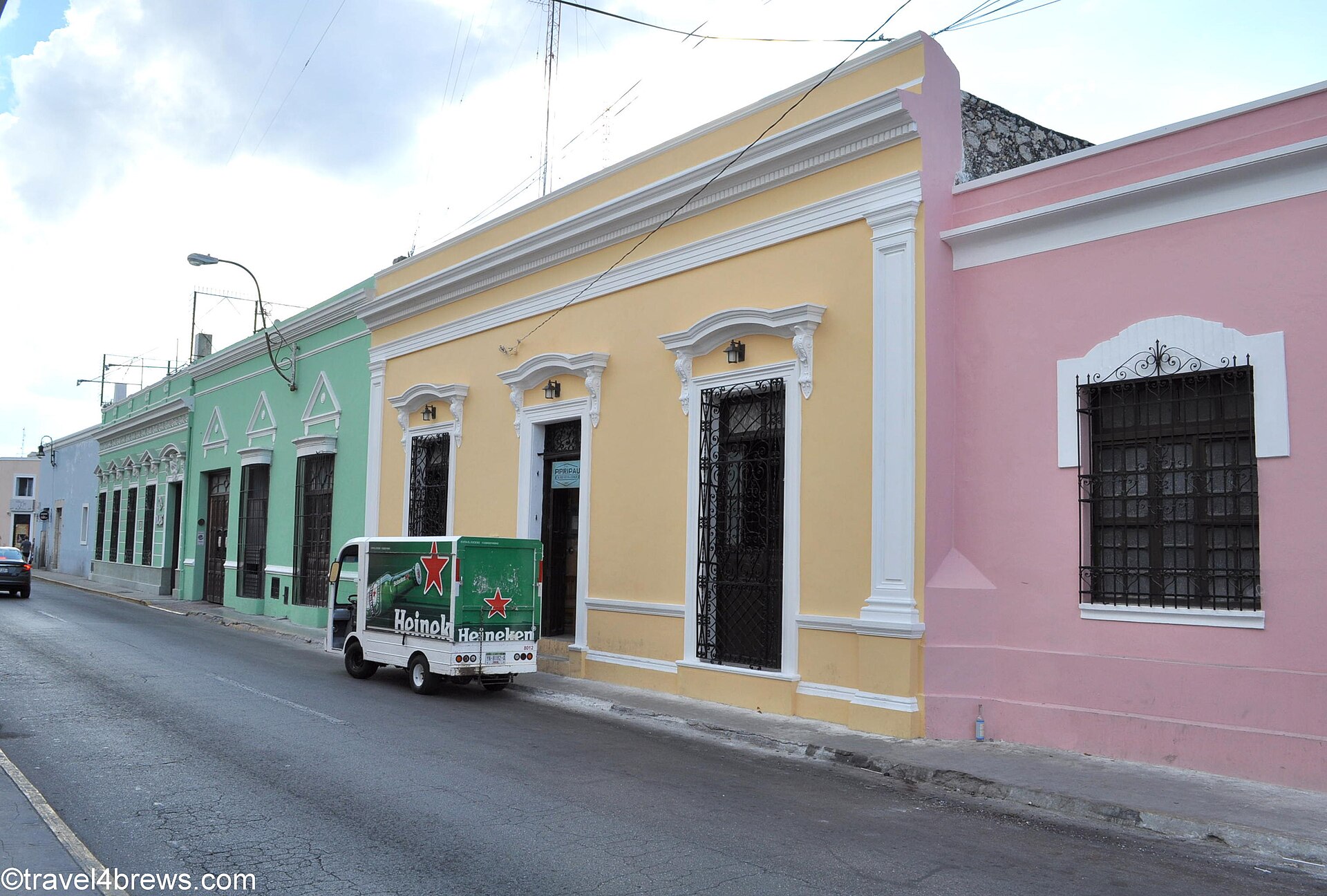 Street scene in Mérida, Yucatán with trees, crosswalk markings, and low-rise city buildings.