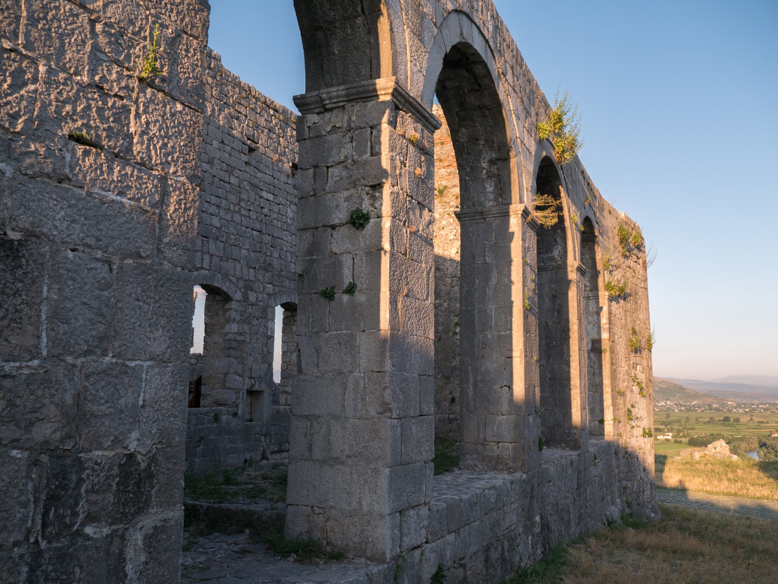 Historic stone structures inside Rozafa Castle above Shkoder under a clear sky.