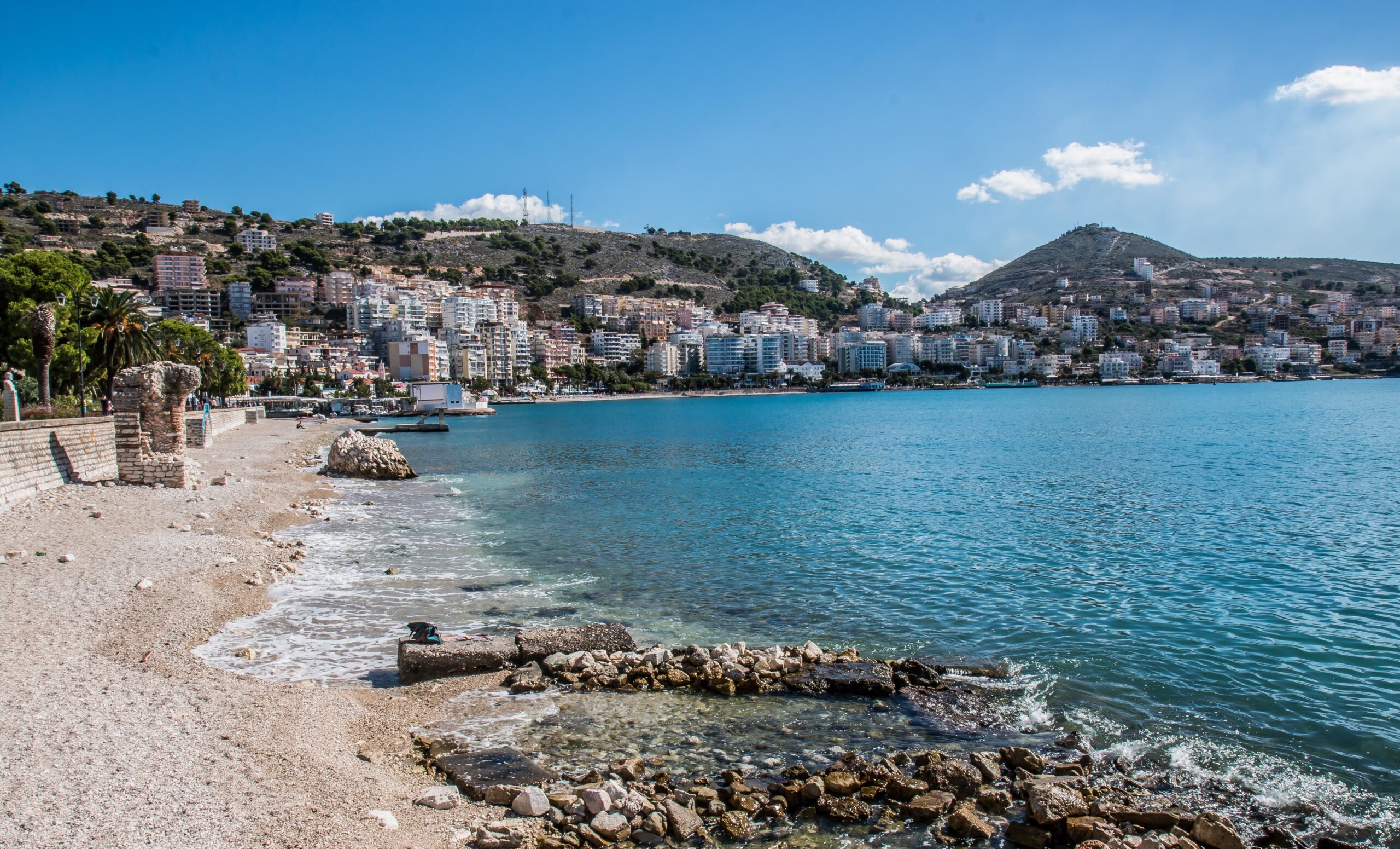 Elevated view over Saranda and the curve of the bay with layered hillside buildings.