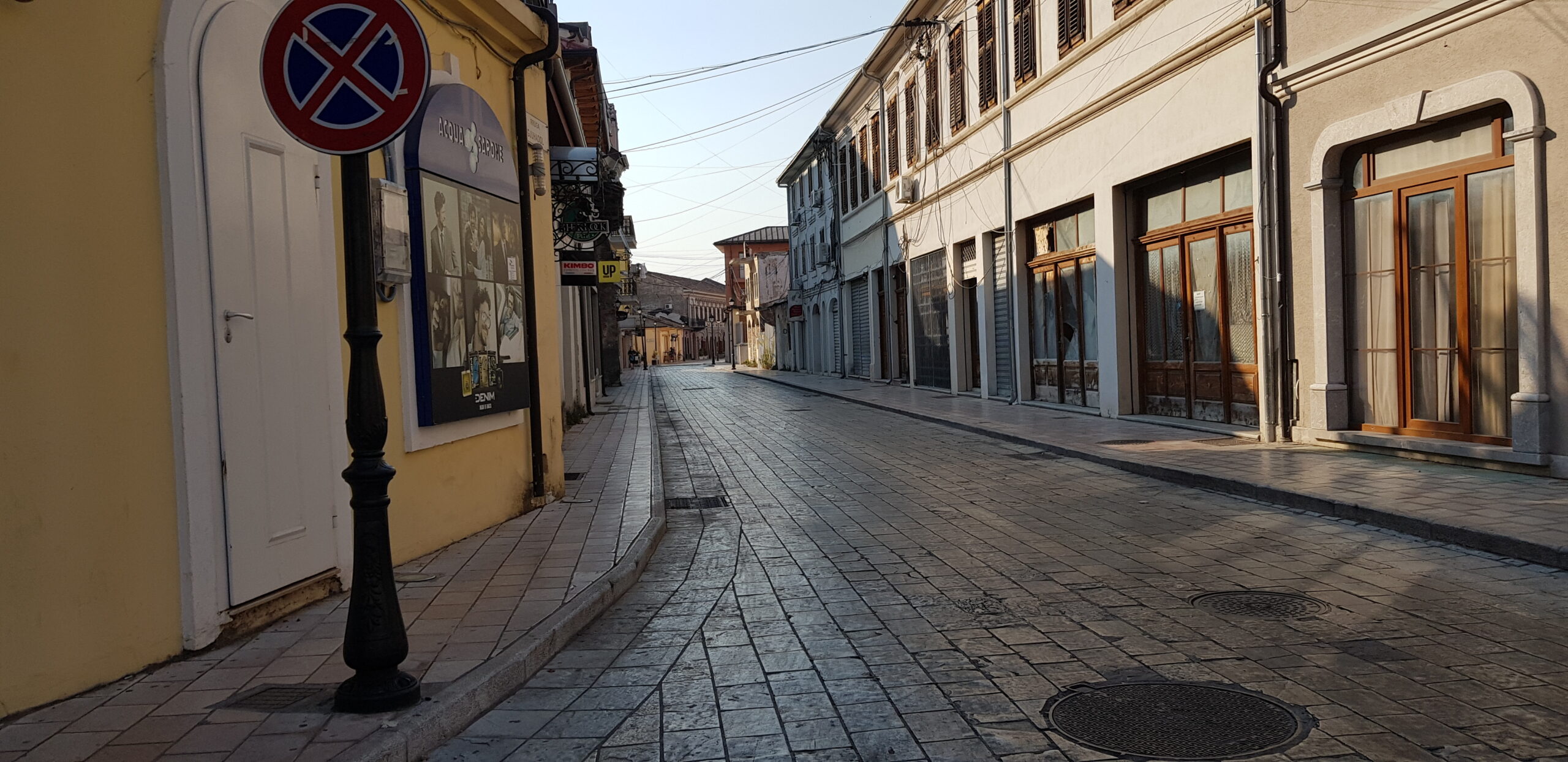 Everyday street scene in Shkoder with low-rise buildings and storefronts.