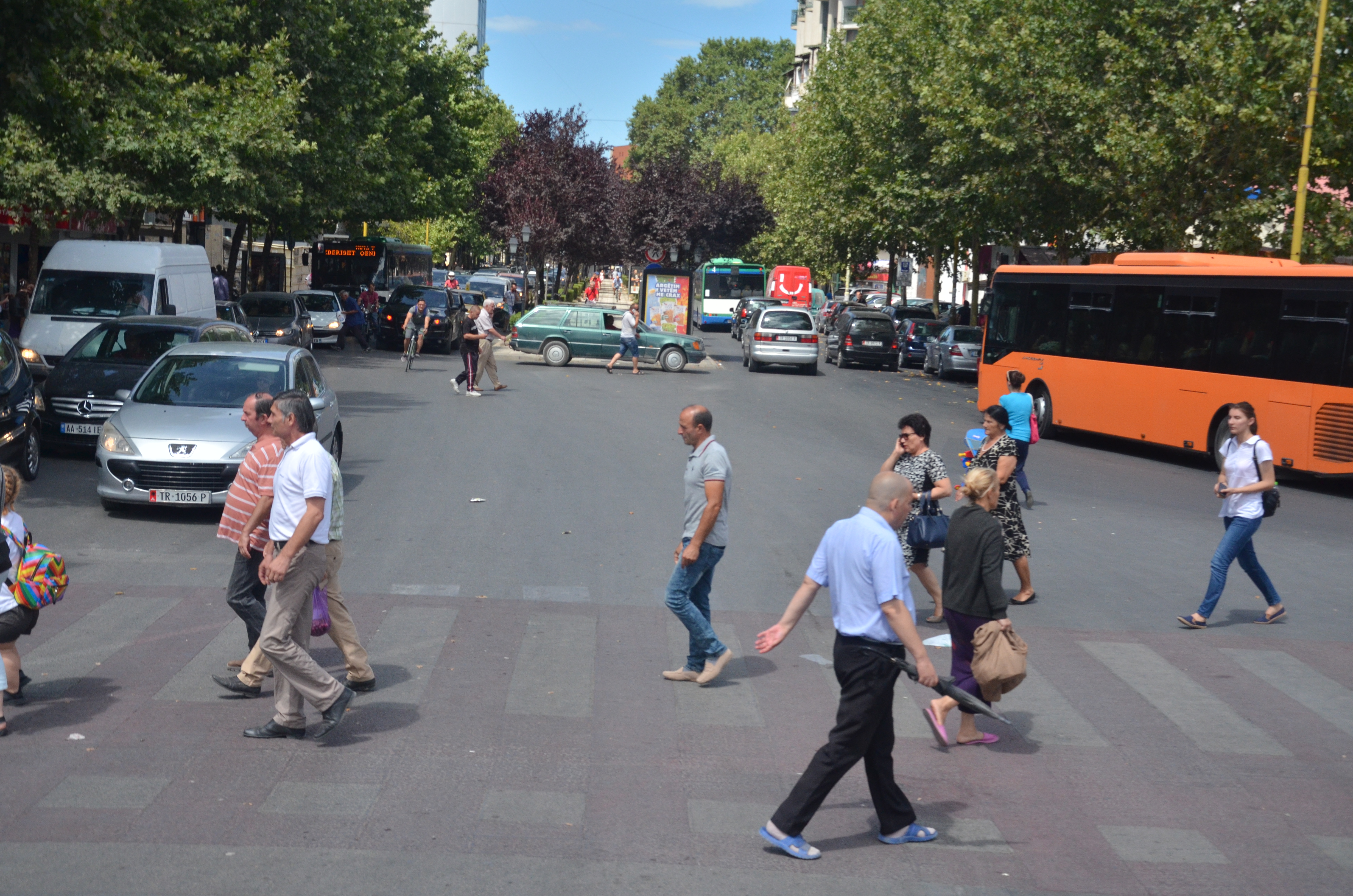 Busy street crossing in a city neighborhood, useful for thinking about how sidewalks, crossings, and traffic affect daily walkability.