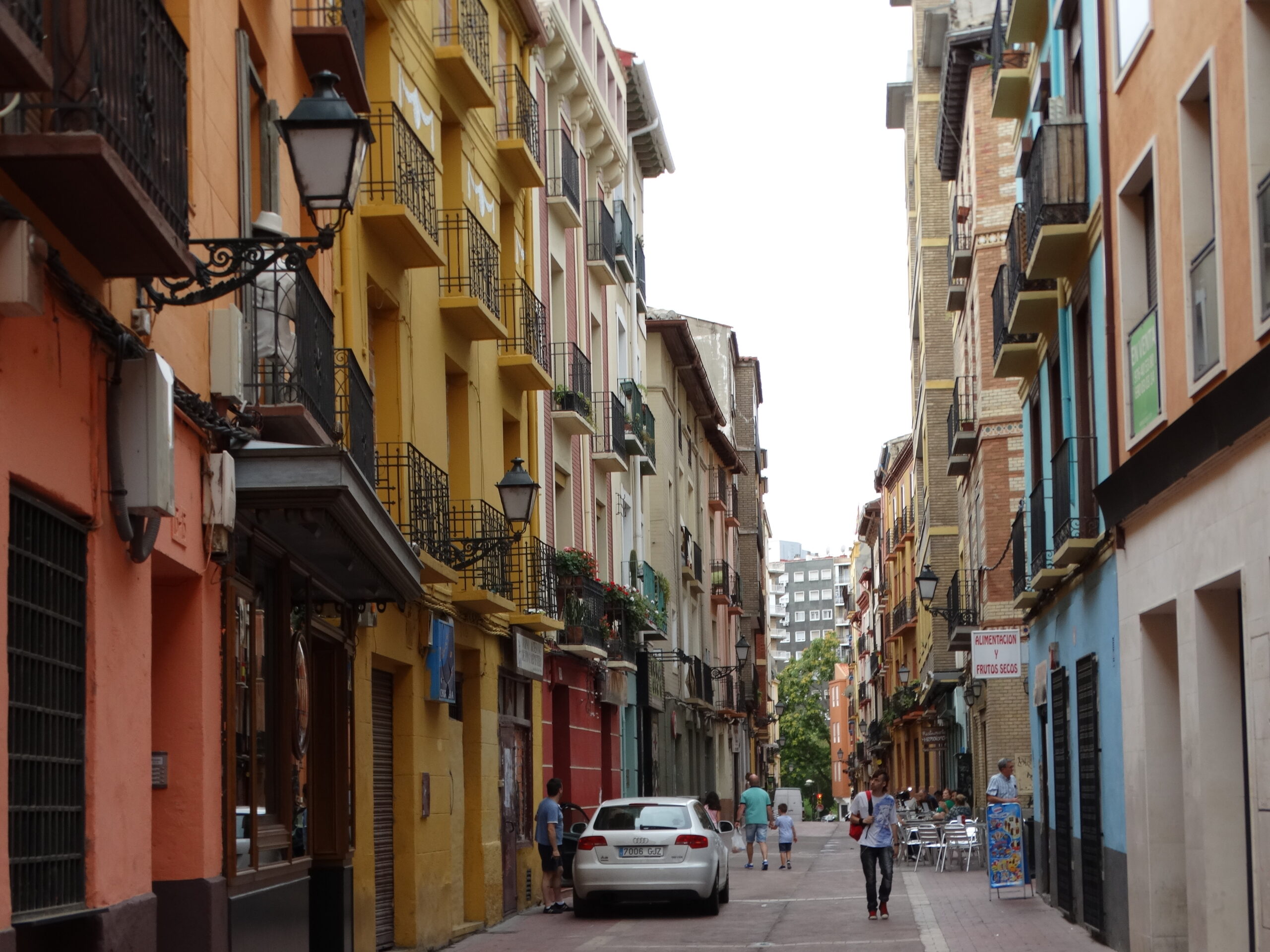 Downtown Zaragoza street scene with pedestrians, storefronts, and mid-rise urban buildings.
