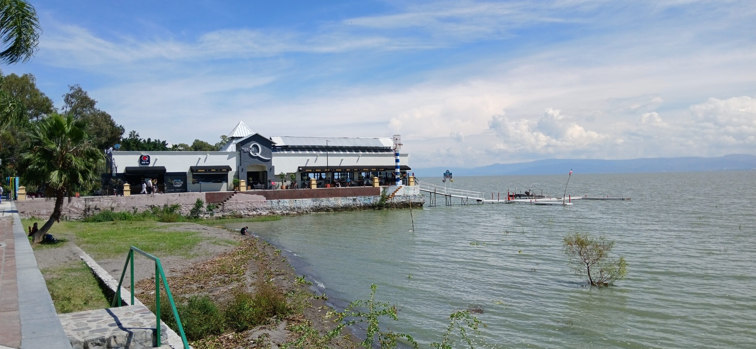 Lake Chapala with a pier, buildings near the water, and mountains in the background.