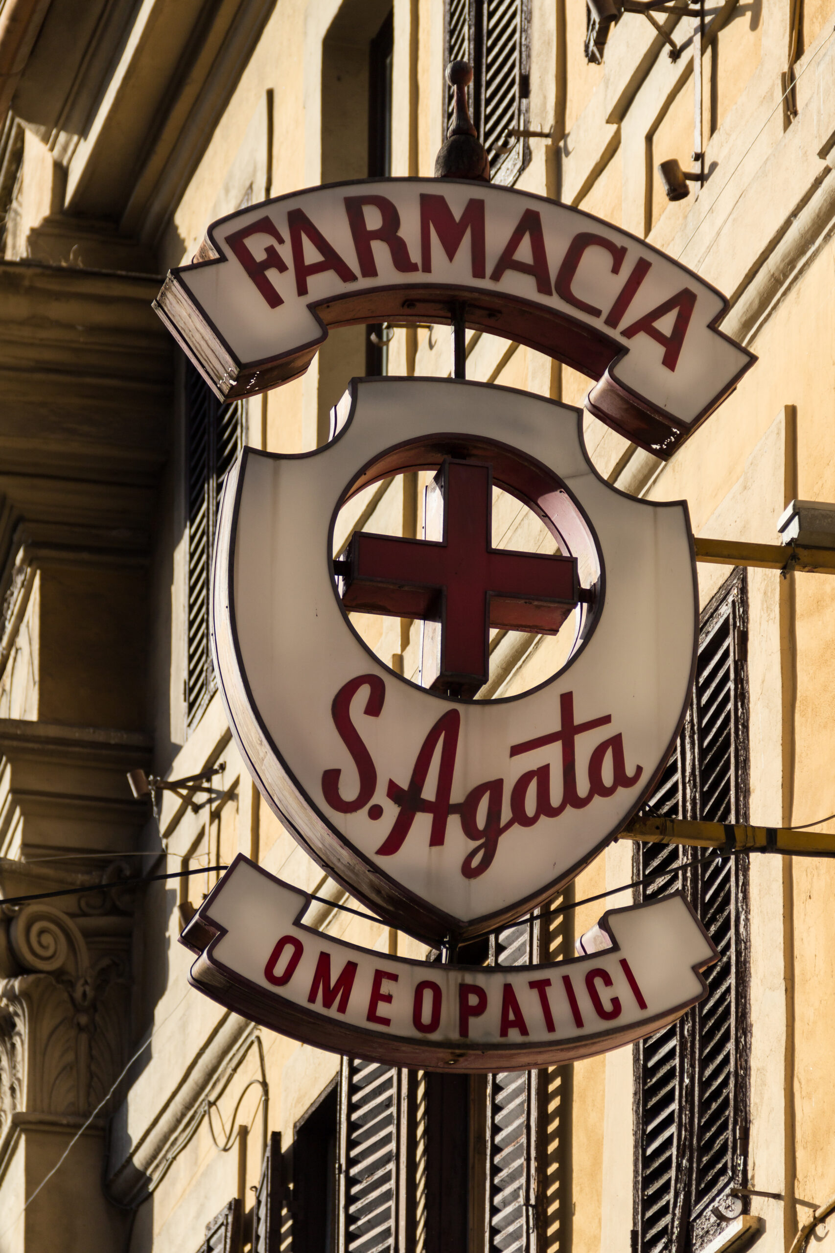 Pharmacy sign on a Rome street, illustrating why everyday healthcare access should be checked alongside rent and errands before choosing a base abroad.