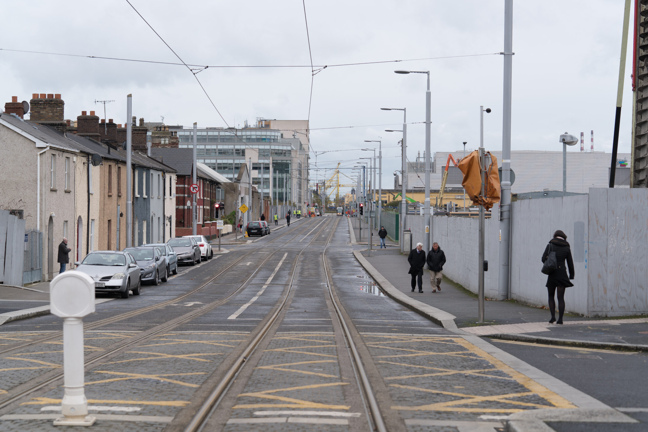 A tram stop and tracks beside apartment buildings on an ordinary urban street in Dublin.