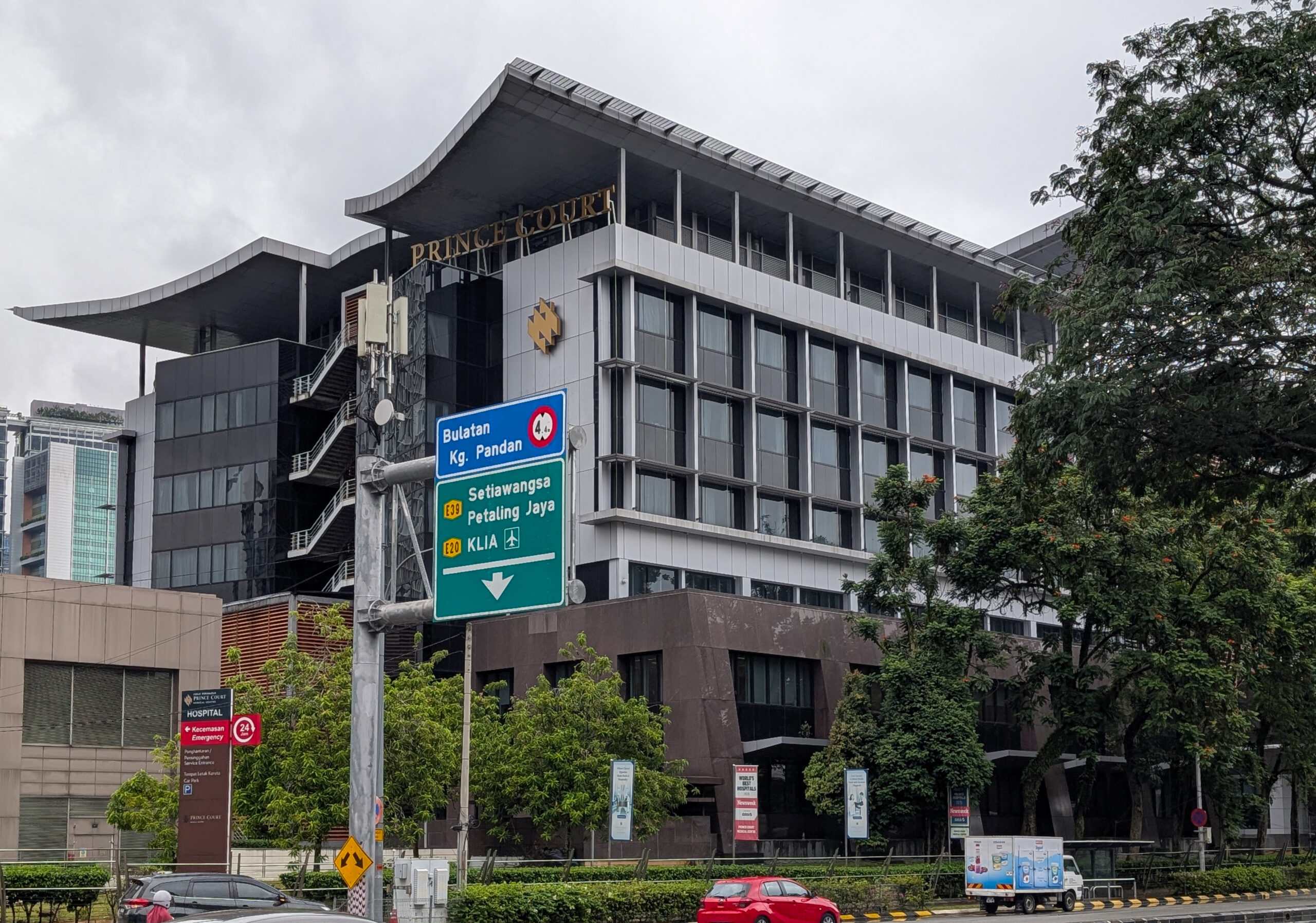 Exterior of Prince Court Medical Centre in Kuala Lumpur, Malaysia, with city traffic and trees in front.