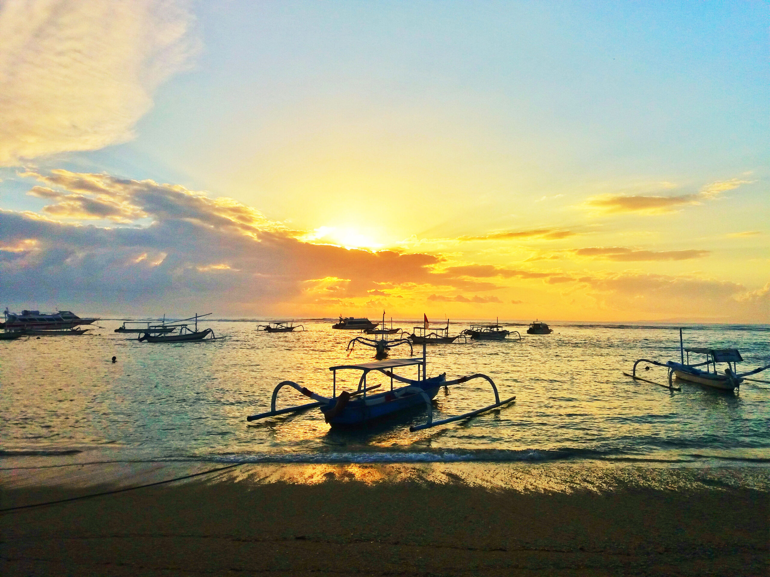 Morning view of Sanur Beach in Bali with boats near the shore.