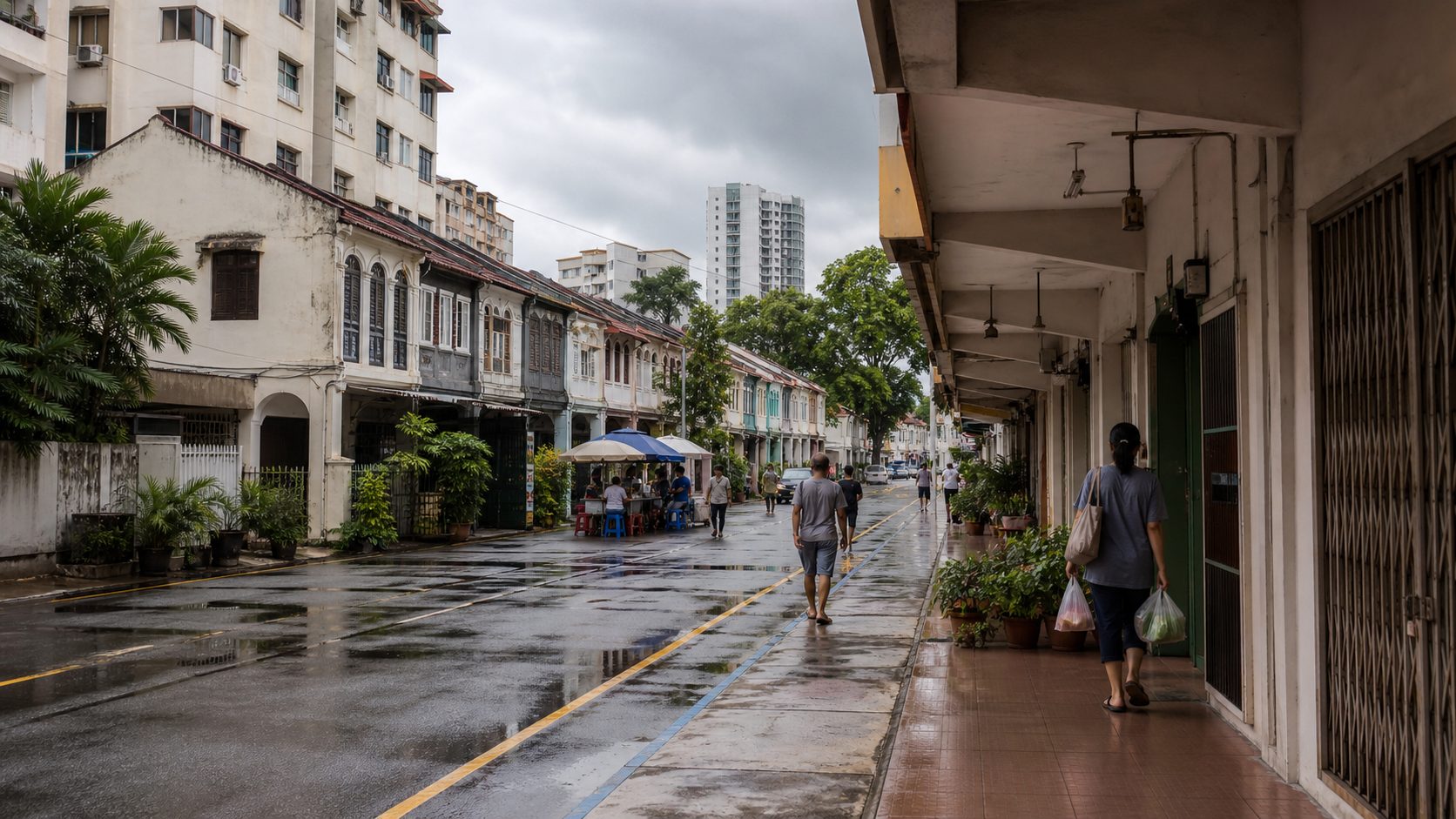 Penang George Town street after rain with heritage shophouses, apartments, a covered sidewalk, tropical greenery, and everyday pedestrians.